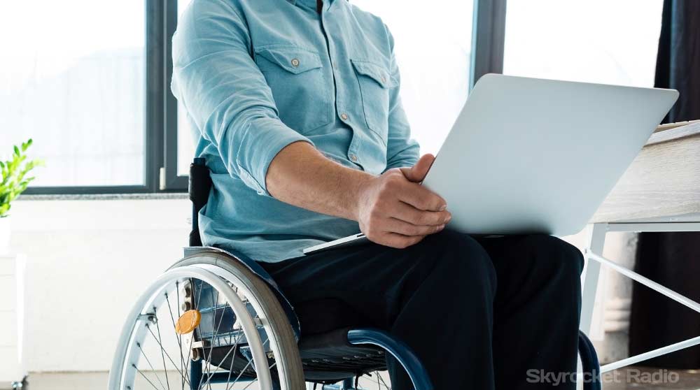 Man in wheelchair reading a laptop.